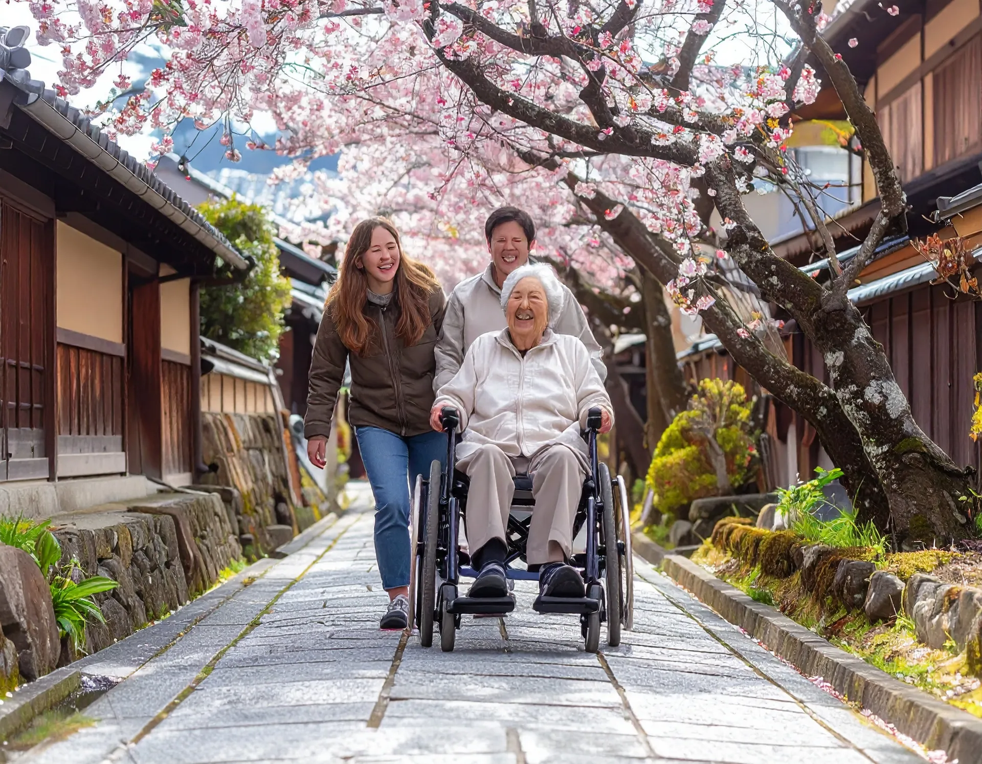 Family pushing a wheelchair together on a sunny street in Kyoto